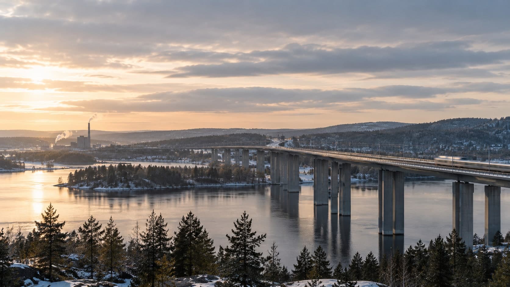 A high bridge across an inlet in low light, with a train crossing.